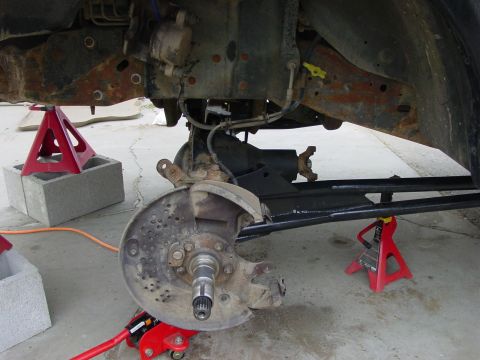 1994 Ford Bronco - Vehicle's undercarriage is supported by jack stands, revealing suspension and brake parts.