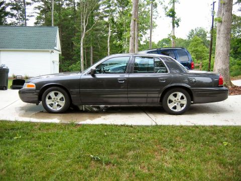 1985 Ford LTD Crown Victoria - This dark gray sedan is parked on a concrete driveway next to a blue SUV.