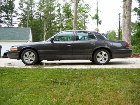 1985 Ford LTD Crown Victoria - This Ford Crown Victoria sedan is shown from its side profile on a paved surface with grass in the foreground.
