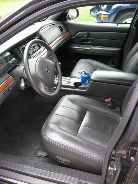1985 Ford LTD Crown Victoria - The interior of a Ford Crown Victoria shows a blue cup in the center console and leather seats.