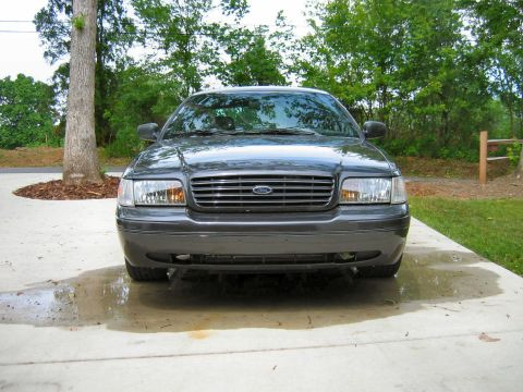 1985 Ford LTD Crown Victoria - Dark gray Ford Crown Victoria parked on a concrete driveway with puddles.