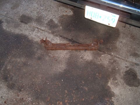 1990 Ford Ranger - A heavily rusted metal bracket lies on a concrete surface next to a license plate.