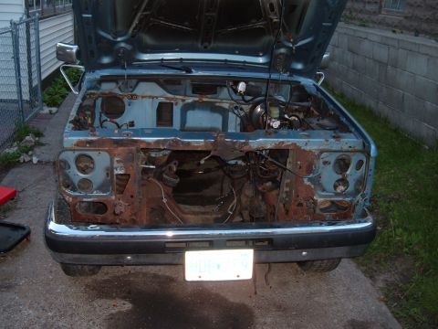 1990 Ford Ranger - Front view of a heavily rusted 1990 Ford Ranger pickup truck with its hood open.