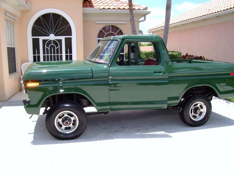 1978 Ford Bronco - Green pickup truck with a side view, parked on a driveway in front of a house.