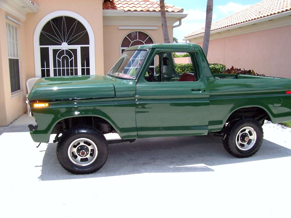 Green pickup truck, side view, parked on driveway