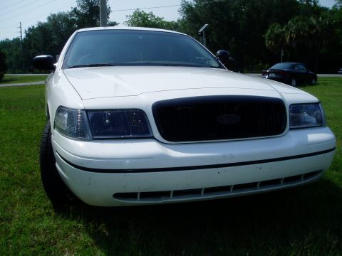 2000 Ford Crown Victoria - A white 2000 Ford Crown Victoria is shown from the front, with a black grille and tinted headlights.