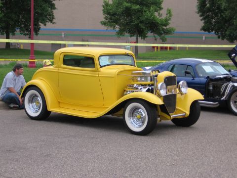 1989 Ford Mustang - A yellow hot rod coupe is parked next to a blue car at an outdoor event.