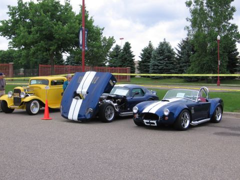 1989 Ford Mustang - A blue convertible with white racing stripes is parked next to other vehicles.