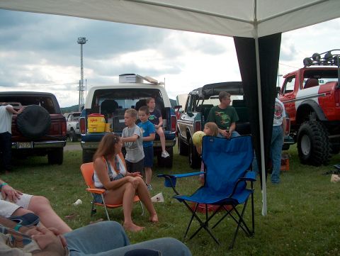 1978 Ford Bronco - Several Ford Broncos are gathered at an outdoor event, with people relaxing under a canopy.