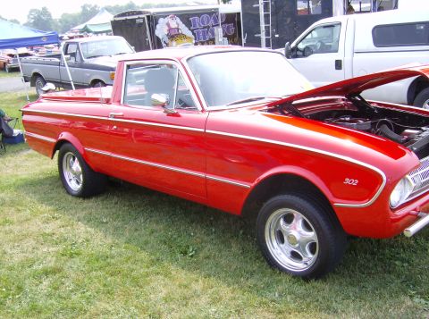 1970 Ford Ranchero - Red pickup truck, possibly a Ford Falcon Ranchero, with hood open. Other vehicles and tents in background.
