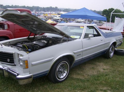 1970 Ford Ranchero - A light-colored Ford Ranchero with its hood open is displayed at an outdoor event with other vehicles and tents in the background.
