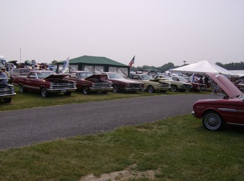 1970 Ford Ranchero - A collection of vintage vehicles are displayed under a hazy sky at what appears to be a car show.