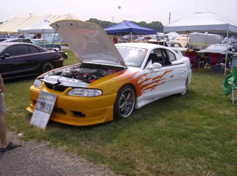 1970 Ford Ranchero - A custom coupe with a two-tone paint job and flame graphics is displayed with its hood open at an outdoor event.