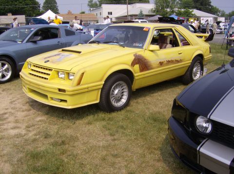 1970 Ford Ranchero - Yellow 1980s Ford Mustang hatchback features a custom mural of horses on its side.
