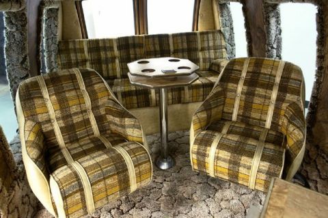 1978 Ford E250 - The interior of a van features plaid upholstery on its seats and bench, with a central table.