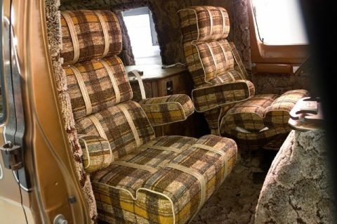 1978 Ford E250 - The plush, plaid interior of a van features captain's chairs and wood paneling.