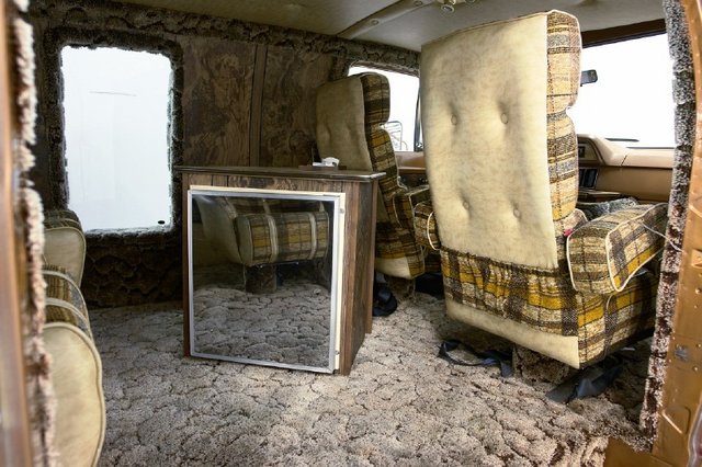 1978 Ford E250 van interior showing plaid seats, carpet, and a small refrigerator