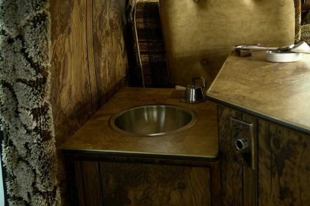 Sink and counter in a van interior with wood paneling and shag carpet