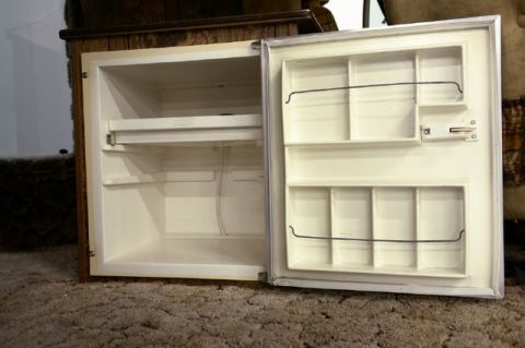1978 Ford E250 - An open refrigerator with a wood-paneled exterior sits on a carpeted floor.