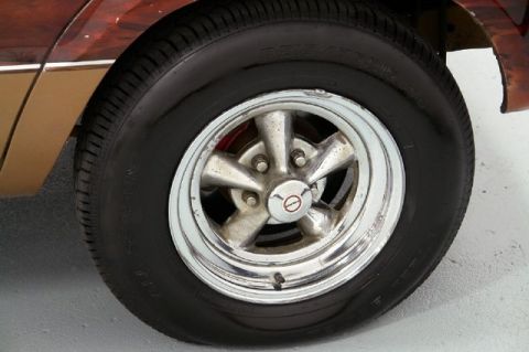 1978 Ford E250 - A close-up shot of a vehicle's wheel and tire, showing custom rims and wood paneling on the body.
