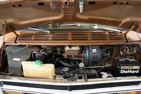 1978 Ford E250 - The engine bay of a brown van, a DieHard Gold battery and various engine components.