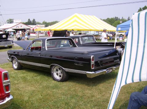 1970 Ford Ranchero - A black Ford Ranchero pickup truck is parked on grass next to other vehicles under tents.