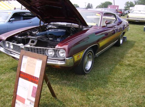 1970 Ford Ranchero - A maroon 1970 Ford Torino GT is displayed with its hood open, showing the engine and a sign detailing its mileage.