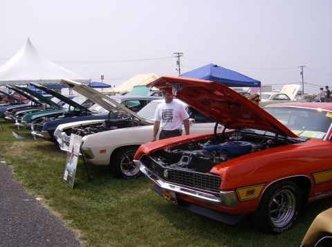 1970 Ford Ranchero - Multiple classic cars are displayed with their hoods open at an outdoor event, likely a car show.