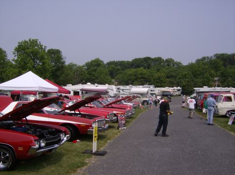 1970 Ford Ranchero - A car show features multiple classic red vehicles and RVs under a cloudy sky.