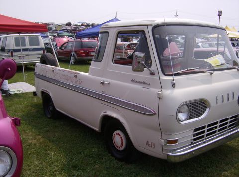 1970 Ford Ranchero - A white 1967 Ford Econoline pickup truck is seen at an outdoor car show with other vehicles and tents in the background.