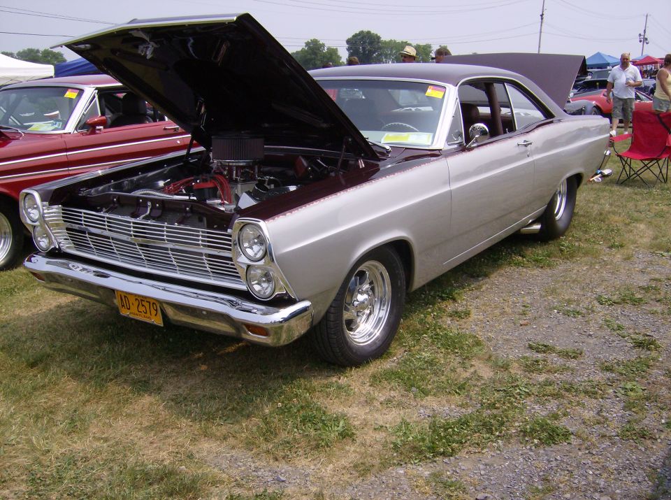 Silver and maroon coupe with hood open, chrome grille, and yellow license plate AD-2579