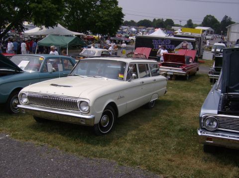 1970 Ford Ranchero - A white station wagon is parked on grass at an outdoor car show, with other vehicles and tents in the background.