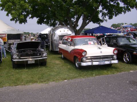 1970 Ford Ranchero - A classic two-tone red and white Ford Fairlane Crown Victoria is displayed at an outdoor event with other vehicles and tents.