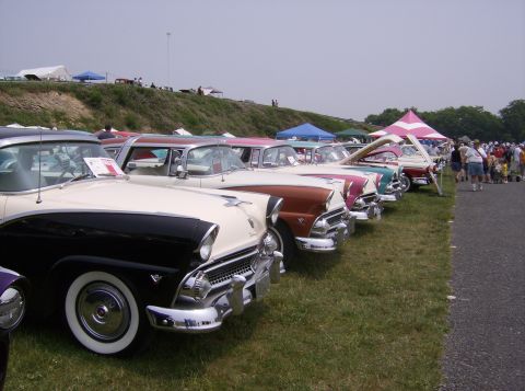 1970 Ford Ranchero - A row of classic cars, including a two-tone 1956 Ford Fairlane Crown Victoria, are displayed on a grassy field.