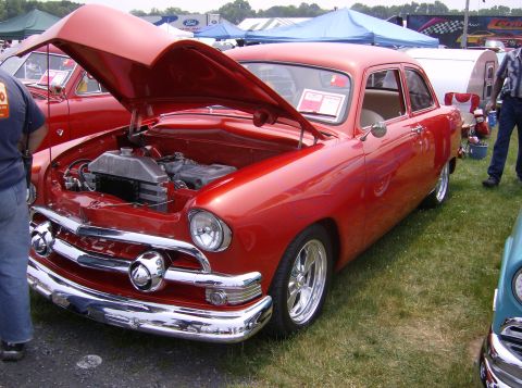 1970 Ford Ranchero - A classic red Ford sedan is displayed with its hood up at an outdoor event.