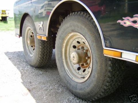 1978 Ford E250 - Close-up of the rear dual wheels on a dark vehicle, flame decals and a horse emblem on the fender.