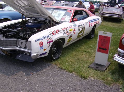 1970 Ford Ranchero - A vintage race car, possibly a 1970 Ford Ranchero, is displayed with its hood open at an outdoor event.