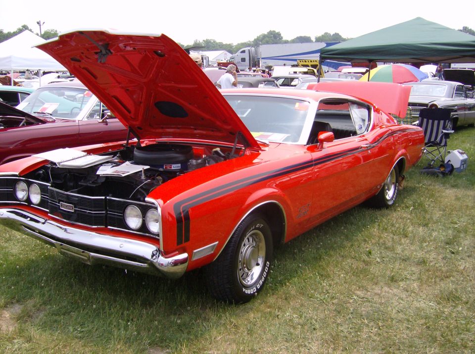 Red 1970 Ford Ranchero with hood open, black racing stripes, and chrome trim. Visible Cooper Cobra tires