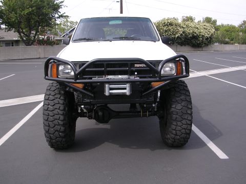 1985 Toyota 4Runner - White Toyota pickup truck modified with a heavy-duty bumper and winch, seen from the front.