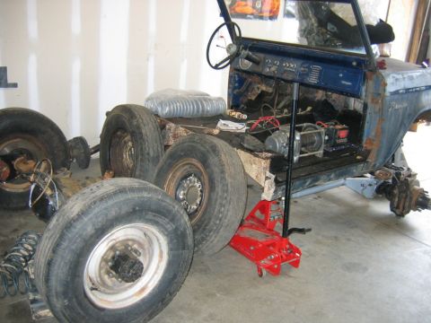 1992 Ford Mustang - A blue Ford Bronco body is shown in a garage during a restoration project, with its wheels removed and interior components visible.