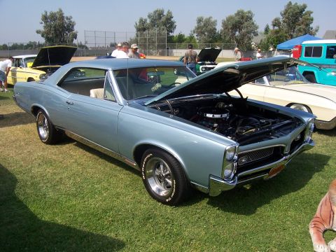2002 Ford Mustang - A light blue 1966 Pontiac GTO coupe is displayed with its hood open at an outdoor event.
