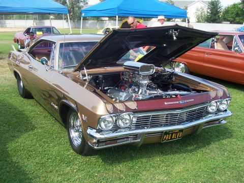 2002 Ford Mustang - This customized classic car, likely a 1965 model, is displayed with its hood open, a powerful engine and custom flame paint job.