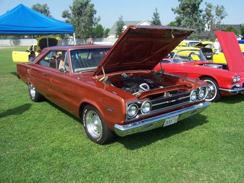 2002 Ford Mustang - Two vintage American muscle cars, a Plymouth GTX and a Chevrolet Corvette, displayed at an outdoor event.