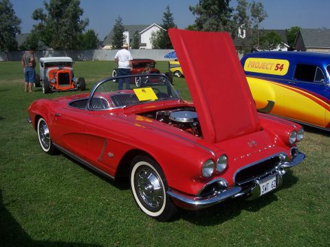 2002 Ford Mustang - A classic red convertible is displayed with its hood open at an outdoor event, alongside other vehicles.