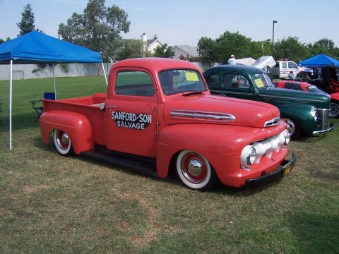 2002 Ford Mustang - A classic red pickup truck with whitewall tires is displayed outdoors next to other vintage vehicles.