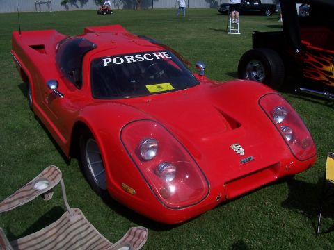 2002 Ford Mustang - A red Porsche 917 race car is displayed on a grassy field, with a PORSCHE banner on the windshield and a 917 badge on the front.