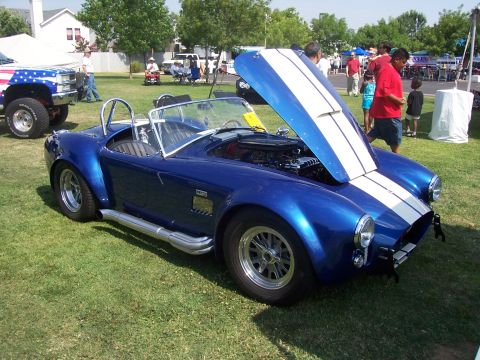 2002 Ford Mustang - A blue convertible with dual white racing stripes is displayed with its hood open at an outdoor event.
