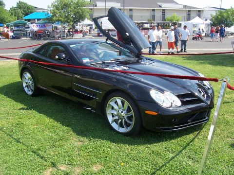 2002 Ford Mustang - A black Mercedes-Benz SLR McLaren is displayed with its distinctive gullwing doors open.