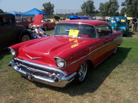 2002 Ford Mustang - A classic red 1957 Chevrolet Bel Air is displayed at an outdoor car show.