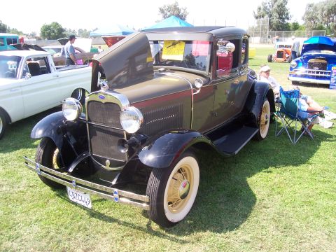2002 Ford Mustang - A classic Ford Model A coupe is displayed at an outdoor event, with other vehicles visible in the background.